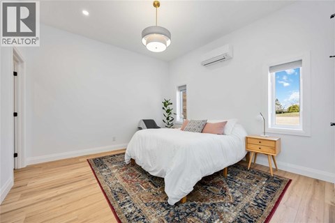 A bedroom with a white bed and a rug on the floor.