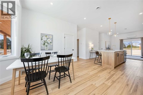 A dining room with a table set for two and a kitchen area in the background.