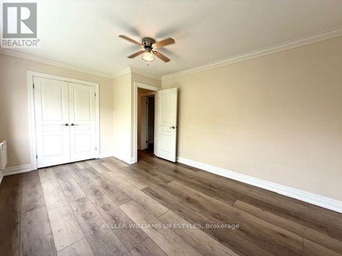 A room with a ceiling fan and wooden flooring.