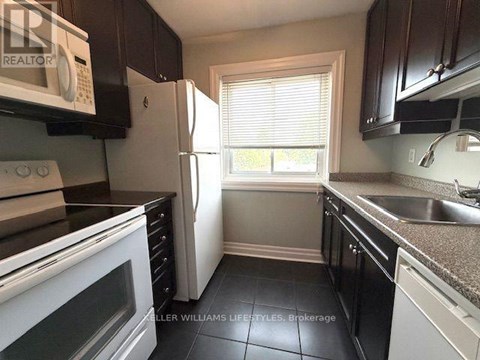 A kitchen with black cabinets and a white refrigerator.