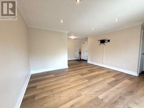 A spacious room with wooden flooring and white walls.