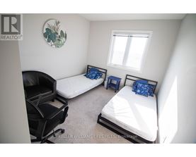 A bedroom with two beds and a chair.