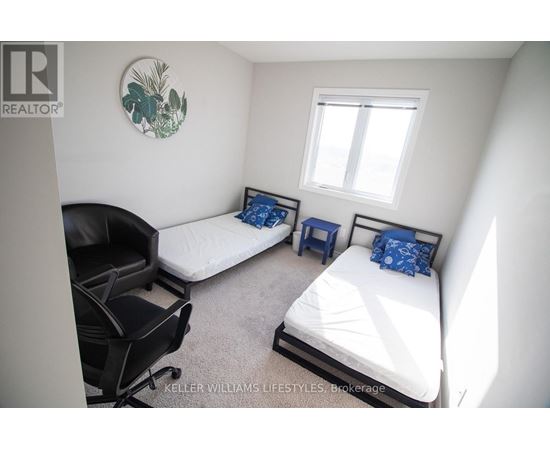 A bedroom with two beds and a chair.