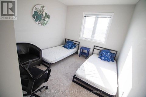 A bedroom with two beds and a chair.