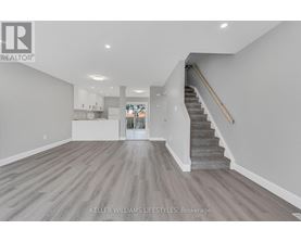 A spacious living room with a staircase leading to the upper floor.