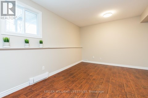 A room with wooden flooring and a window with three potted plants on the windowsill.