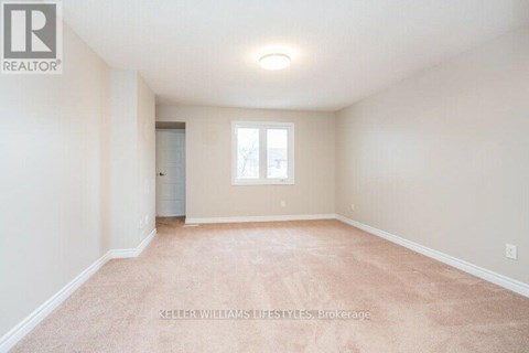 A spacious room with a carpeted floor and a window.