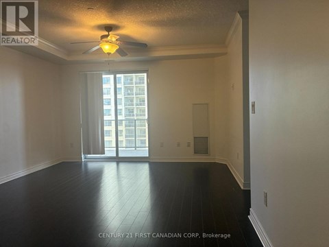 A spacious room with a ceiling fan and sliding glass doors leading to a balcony.
