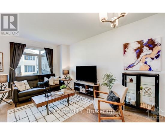 A living room with a black couch, a wooden coffee table, a flat screen TV, and a large painting on the wall.