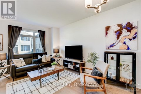 A living room with a black couch, a wooden coffee table, a flat screen TV, and a large painting on the wall.