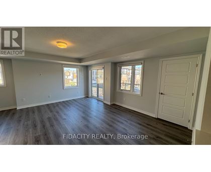 A spacious room with wood flooring and two windows.