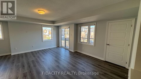 A spacious room with wood flooring and two windows.