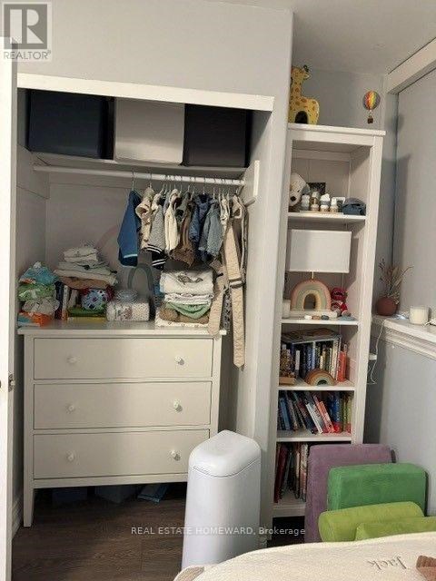 A white closet with clothes hanging and a bookshelf with books.