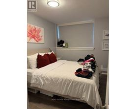 A bedroom with a white bed and a pink flower painting on the wall.