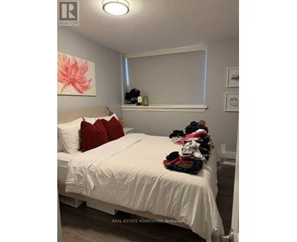 A bedroom with a white bed and a pink flower painting on the wall.