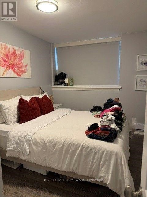 A bedroom with a white bed and a pink flower painting on the wall.