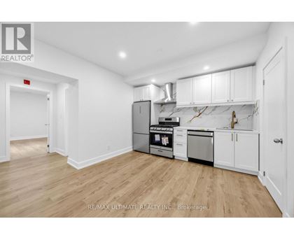 A kitchen with white cabinets and a wooden floor.