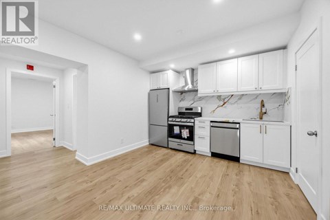 A kitchen with white cabinets and a wooden floor.