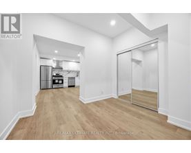 A spacious room with a walk-in closet and a kitchen in the background.