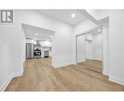A spacious room with a walk-in closet and a kitchen in the background.