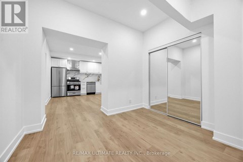 A spacious room with a walk-in closet and a kitchen in the background.