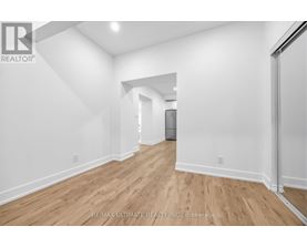 A spacious room with wooden flooring and white walls.