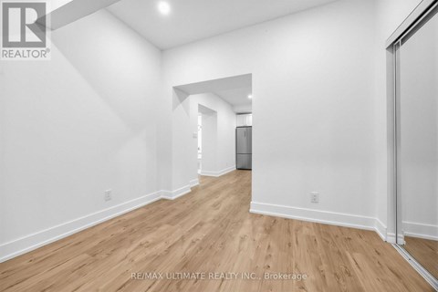 A spacious room with wooden flooring and white walls.