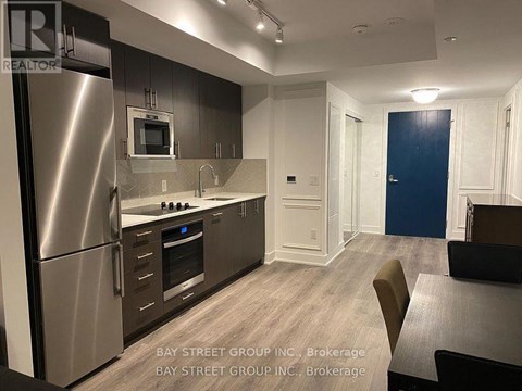 A modern kitchen with a refrigerator, microwave, and oven.