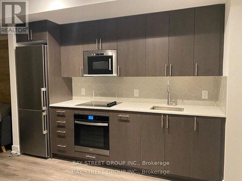A kitchen with a refrigerator, oven, and microwave.