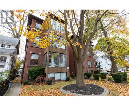A tree with yellow leaves is in front of a brick building.