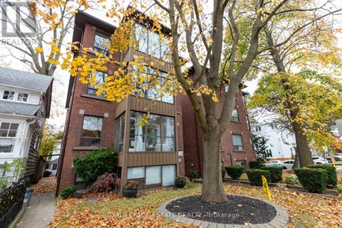 A tree with yellow leaves is in front of a brick building.