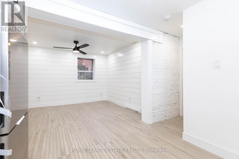 A white room with a ceiling fan and wooden flooring.
