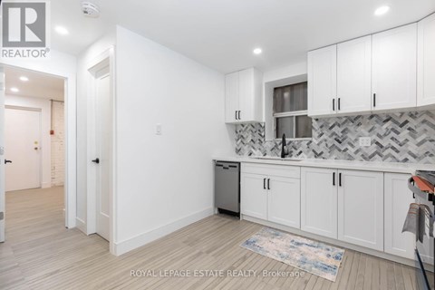 A kitchen with white cabinets and a patterned backsplash.