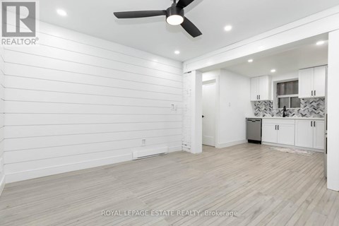 A spacious room with a ceiling fan and lighting fixtures.