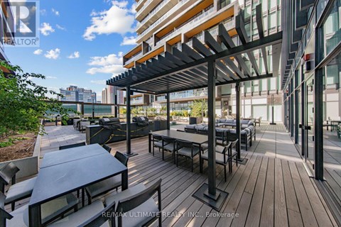 A wooden deck with tables and chairs is surrounded by buildings.