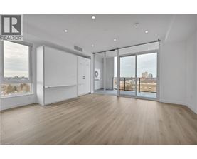 A spacious room with wooden flooring and a large window overlooking a cityscape.