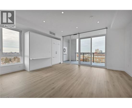 A spacious room with wooden flooring and a large window overlooking a cityscape.