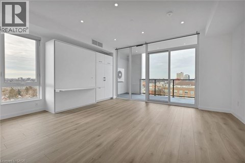 A spacious room with wooden flooring and a large window overlooking a cityscape.