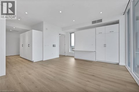 A spacious room with wooden flooring and white cabinetry.