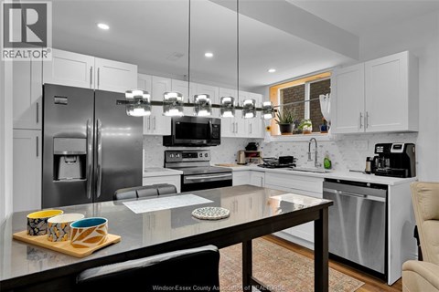 A modern kitchen with a glass table and stainless steel appliances.