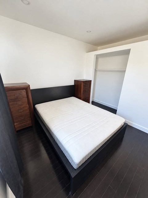 A bed with a white mattress and wooden headboard.