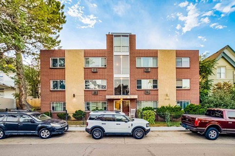 A modern apartment building with cars parked in front.