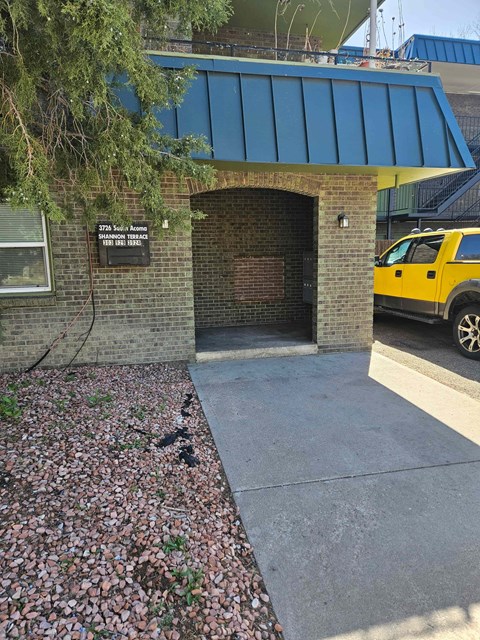 A yellow truck is parked in front of a building with a blue awning.