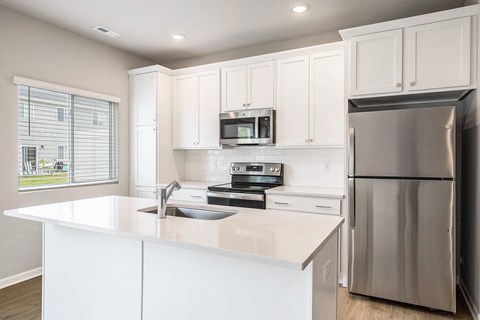 A modern kitchen with white cabinets and stainless steel appliances.