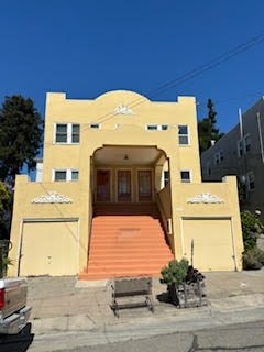 A yellow building with a brown door and steps.