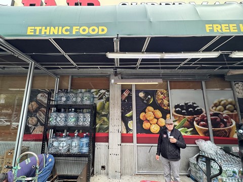 A storefront with a green awning advertising ethnic food.