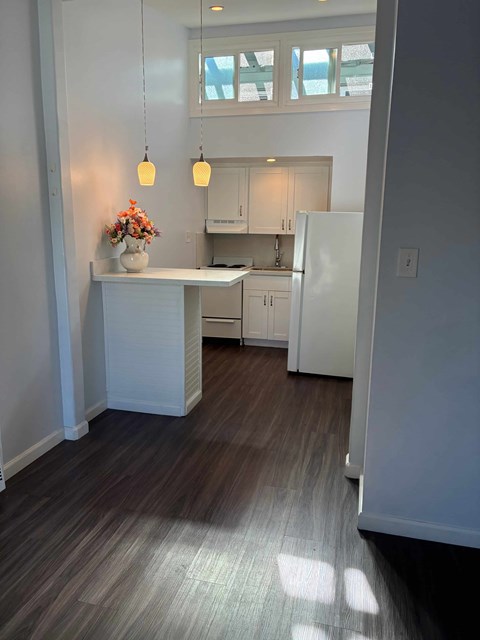 A kitchen with a white island and a white refrigerator.