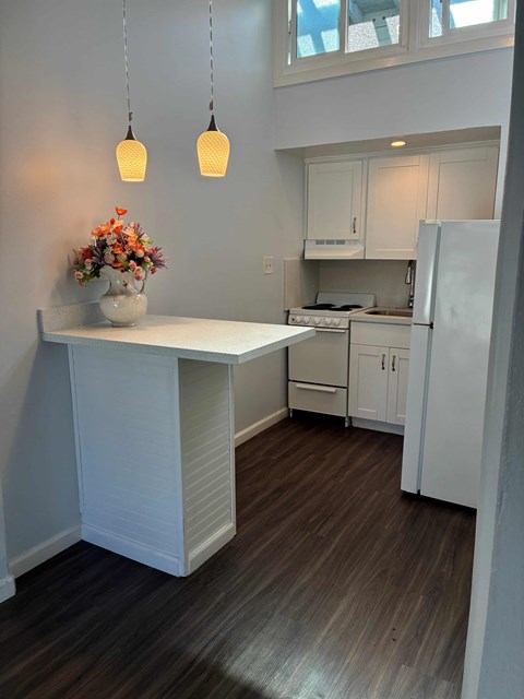 A kitchen with a white island and wooden floors.