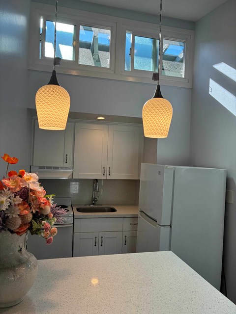 A kitchen with a white fridge, a sink and a window.