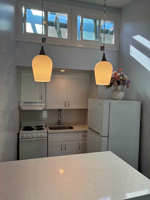 A kitchen with a white counter top and cabinets.